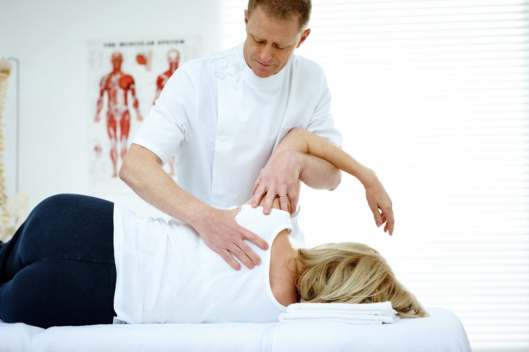 Chiropractor treating shoulder joint problem of a patient